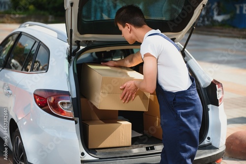 Deliveryman holds parcels at the car, delivering