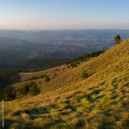 View from the top of Gostilj on the mountain Ozren on the slopes and villages in the valley, a landscape of hilly Balkans with haze on the horizon at evening
