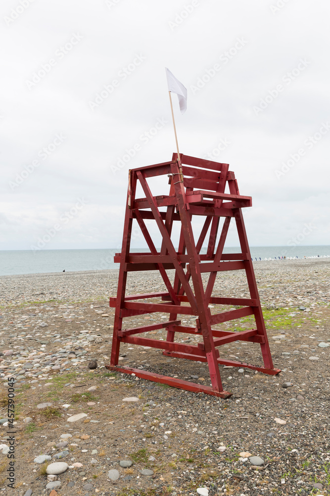Red tower of lifeguards on a pebble beach in the resort town of Batumi Georgia. There are no people, the beach is empty. The sea is in the background. Red tower of lifeguards on a pebble beach in the resort town of Batumi Georgia. There are no people, the beach is empty. The sea is in the background.