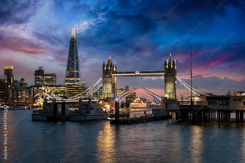 Obraz premium The lifted Tower Bridge and illuminated skyline of London, United Kingdom, during dusk just after sunset