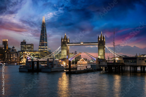 The lifted Tower Bridge and illuminated skyline of London, United Kingdom, during dusk just after sunset