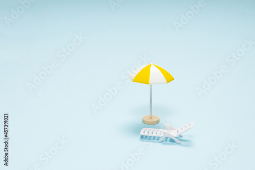 Travel concept. Sun lounger  yellow umbrella on a blue background.