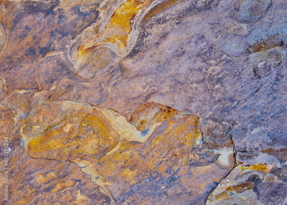 Rough stone texture with rust in blue and yellow colors with orange placed on a wall on a facade