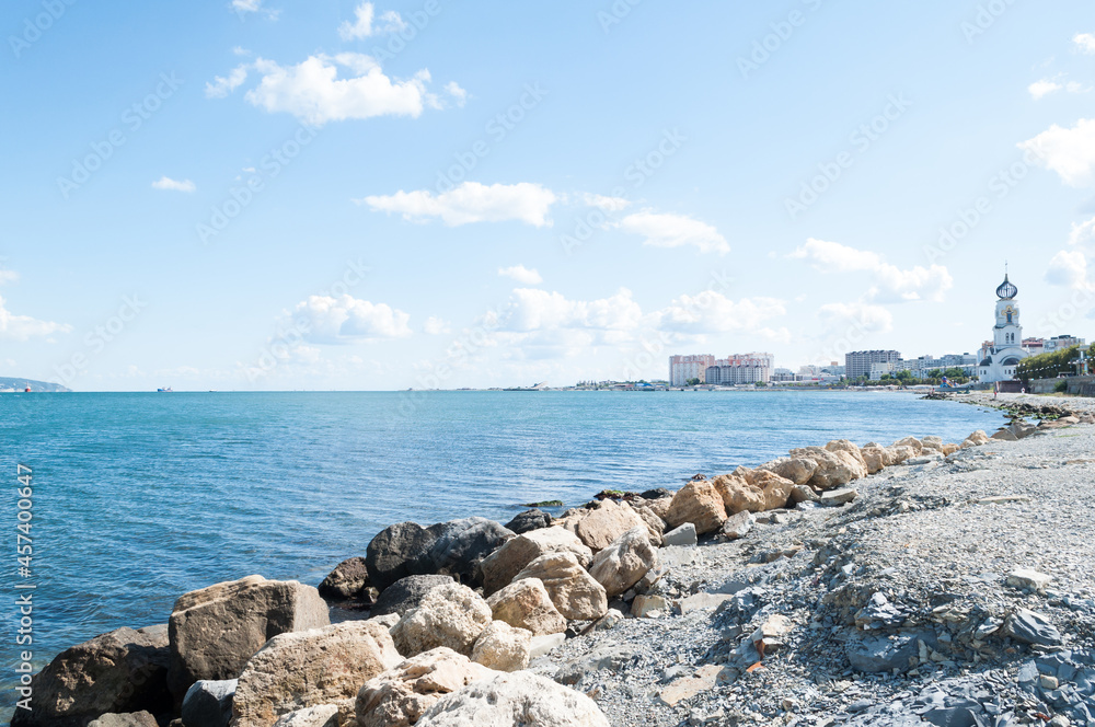 seascape with a pebble beach and a view of the port city. architectural and natural details of the city on the sea. seascape with a pebble beach and a view of the port city. architectural and natural details of the city on the sea.