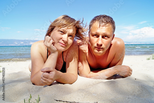 A couple sunbathes on the white sand of Lake Baikal