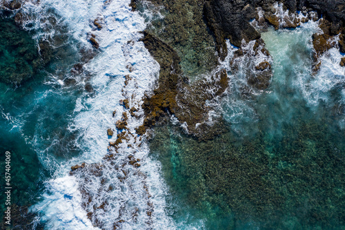 Drone photo of waves crashing against rocks in Hawaii