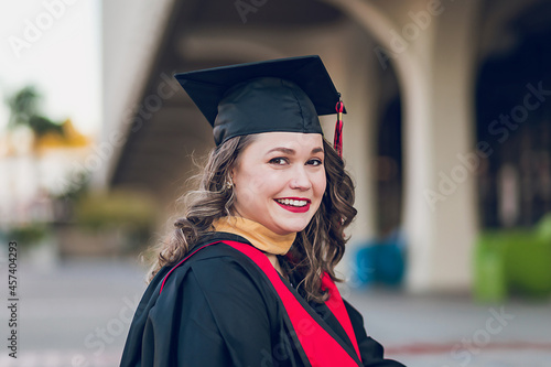 Smiling woman graduating college, wearing a graduation gown/cap.