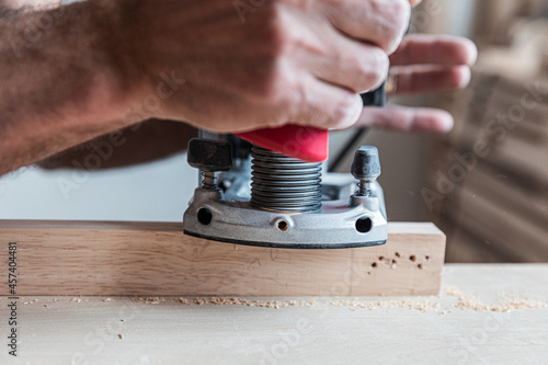 Close-up the male hand processes a wooden board an electric jointer, processing of workpiece