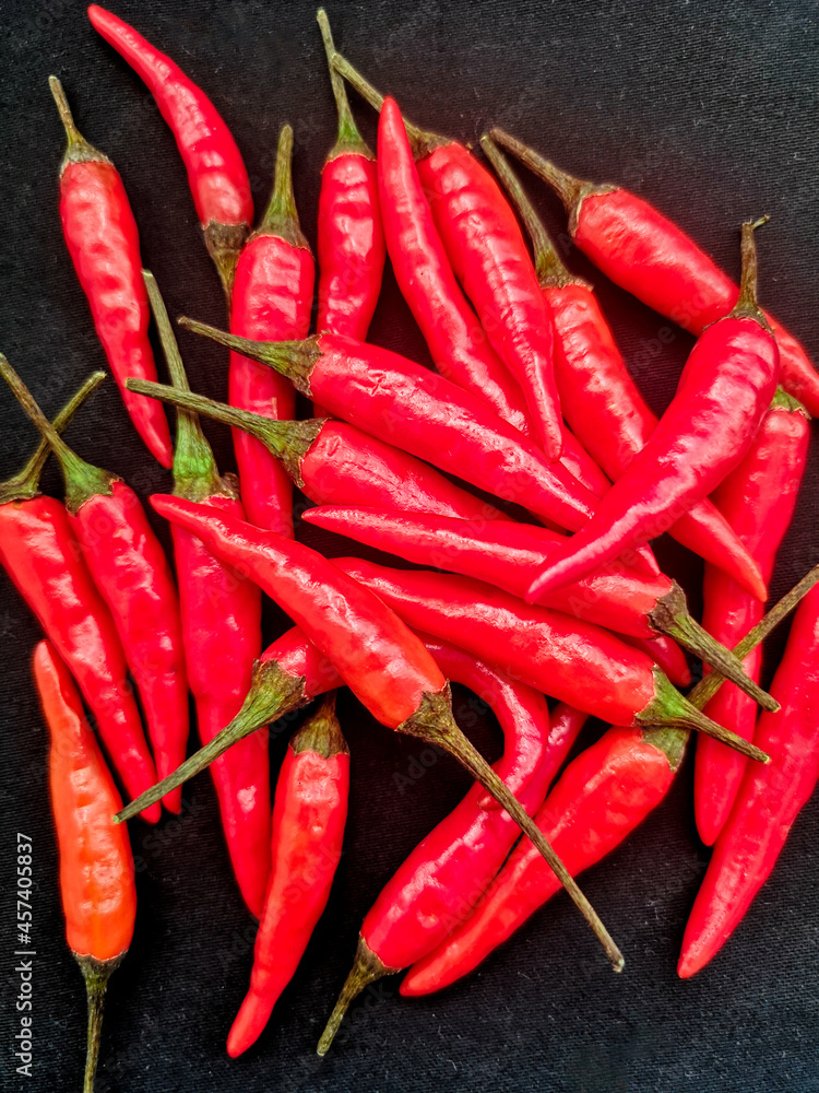 Heap of red hot chili peppers on black background, top view