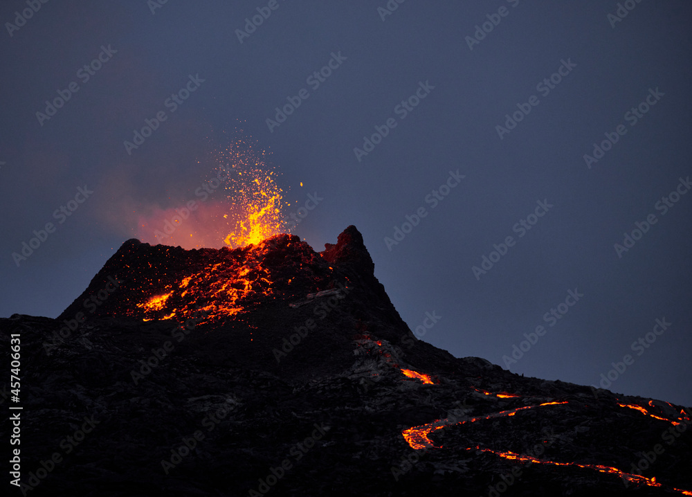 Hot magma erupting from volcanic mountain at night