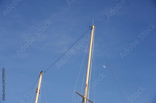 The yacht's masts against the blue sky with the moon.