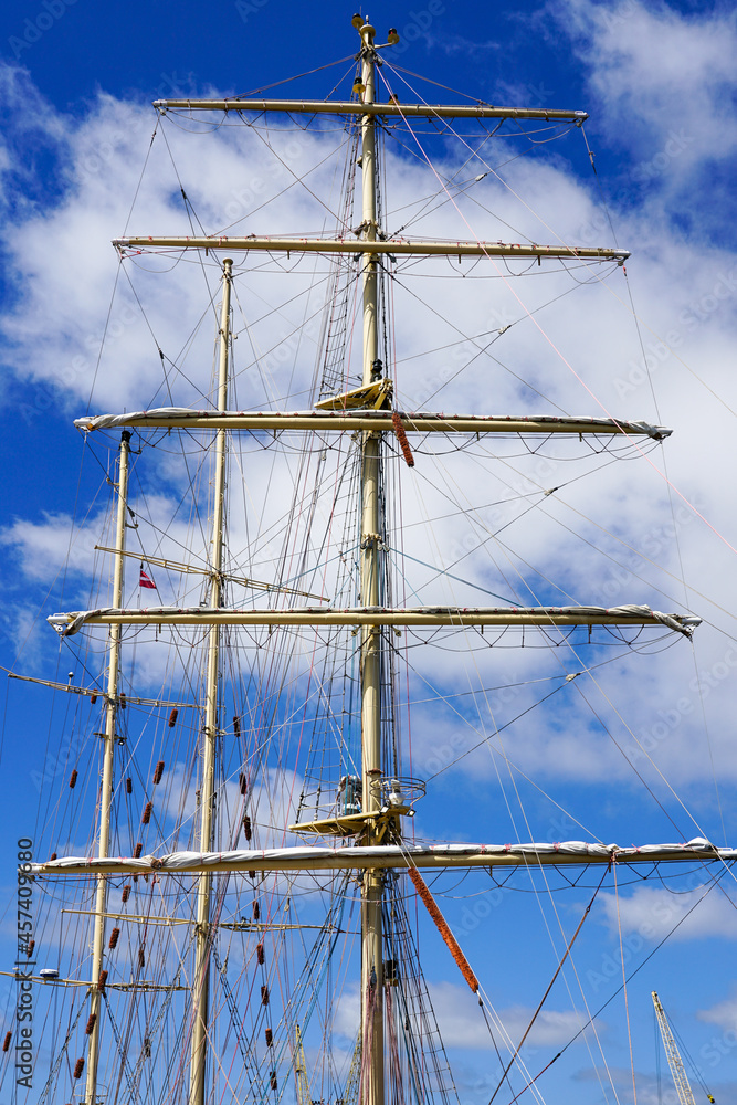 masts of a large sailing ship with ropes on a background of blue sky masts of a large sailing ship with ropes on a background of blue sky