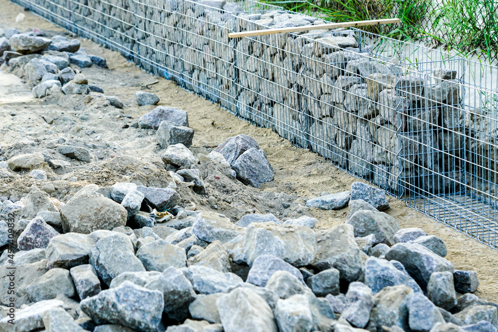 unfinished gabion fence wall construction from steel mesh with stones
