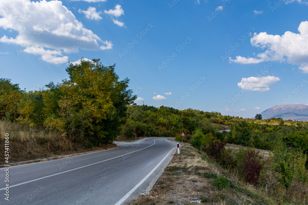 An asphalt empty road on a dry mountain ( Suva Planina ) in Serbia on an autumn day and white clouds in the sky. Beautiful natural background concept