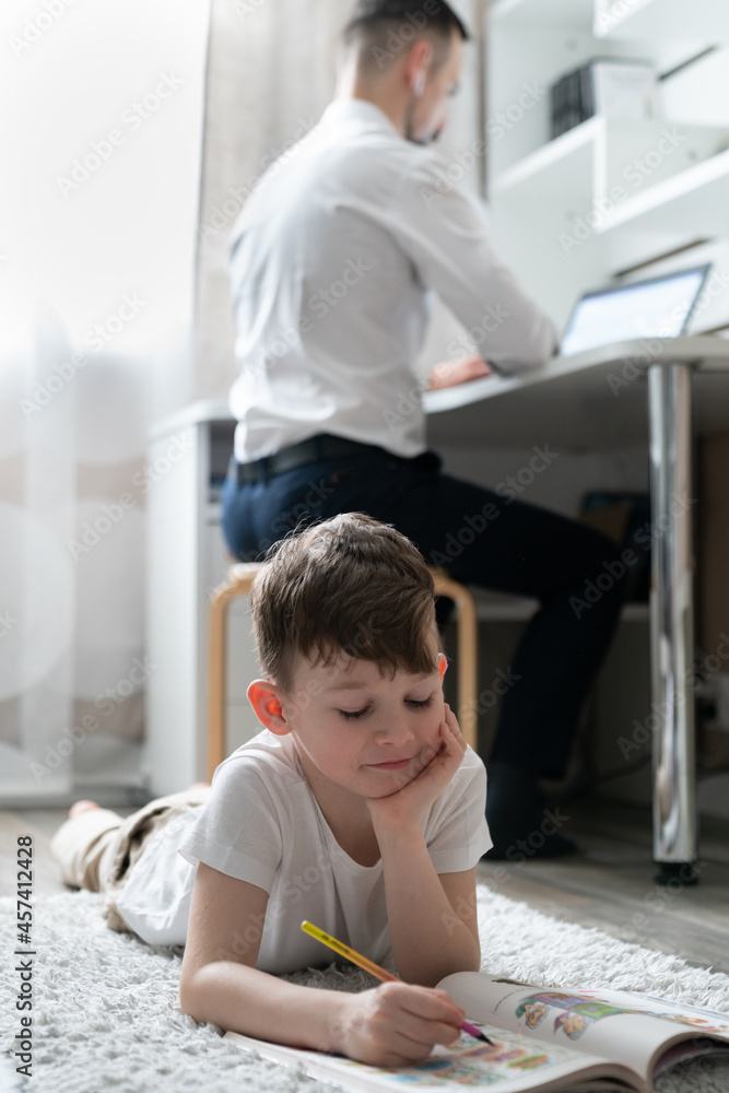boy does homework near father working boy does homework near father working