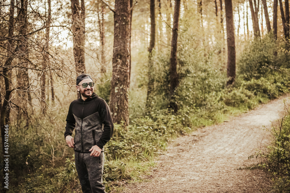 Man with cap and sunglasses smiling in a beautiful forest Man with cap and sunglasses smiling in a beautiful forest