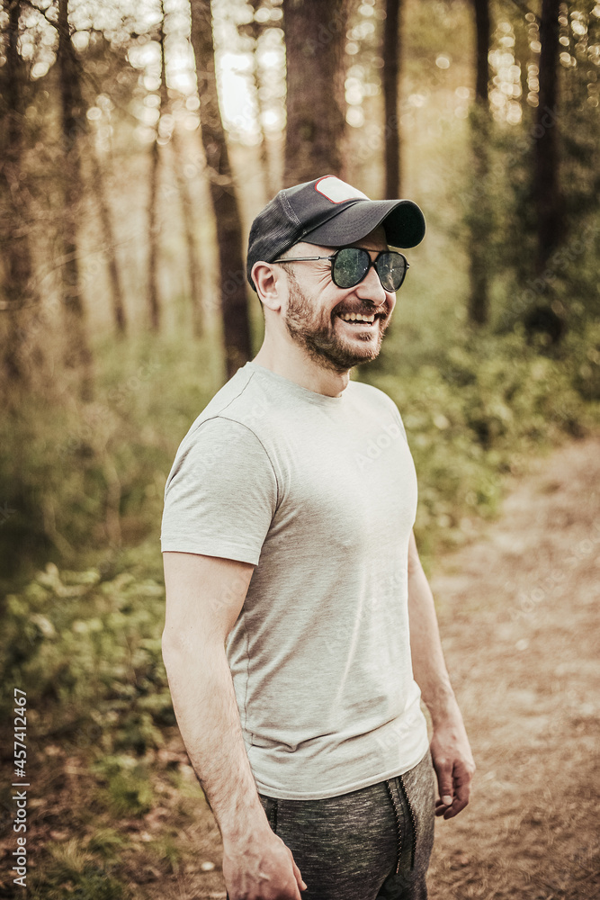Man with cap and sunglasses smiling in a beautiful forest Man with cap and sunglasses smiling in a beautiful forest