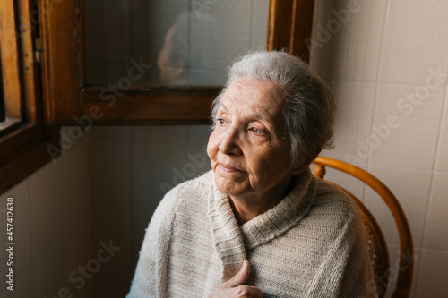 portrait of elderly woman sitting looking out the window photo