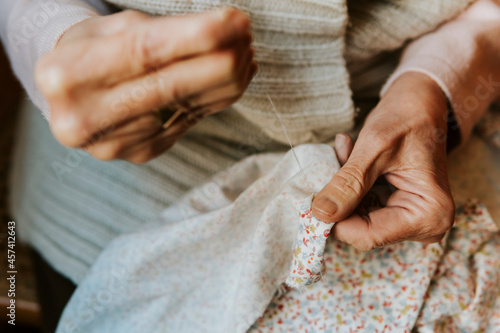 Close up shot of woman's hands sewing with needle and thread
