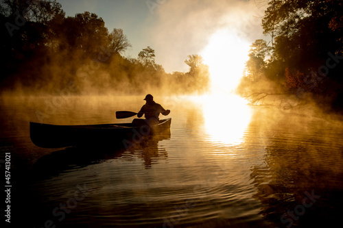 Sunrise canoe ride on foggy river. photo