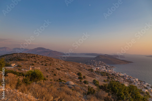 Beautiful sunset view from Lekuresi Castle (Saranda, Albania) to Ionian sea, old concrete bunker, small functioning lighthouse and island Corfu, Greece in the background