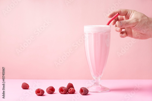 A hand grab a reusable eco-friendly metal straw that is in a raspberry milkshake