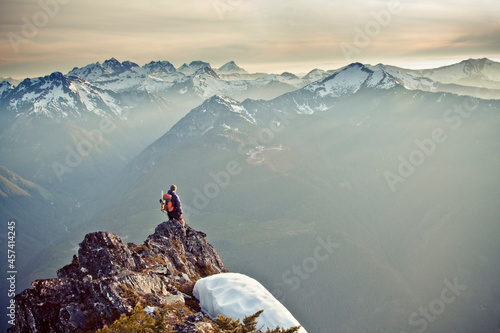 Hiker standing on the edge of a cliff looking out at scenic mountians