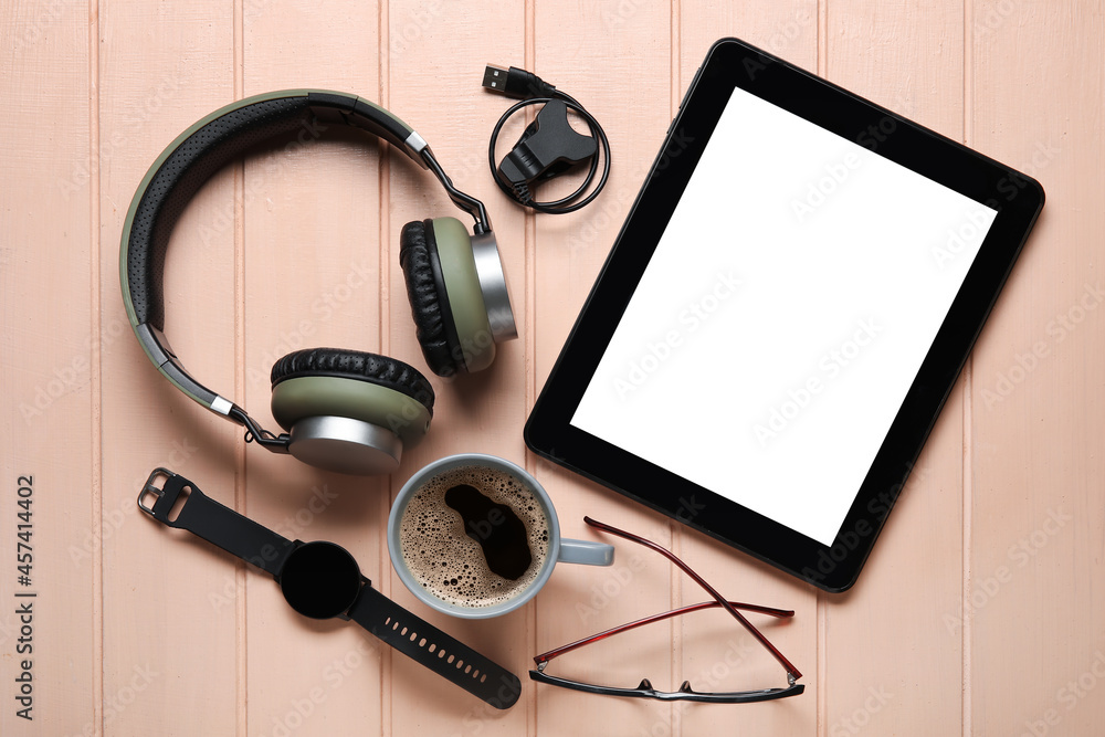 Different modern devices, cup of coffee and eyeglasses on color wooden background Different modern devices, cup of coffee and eyeglasses on color wooden background