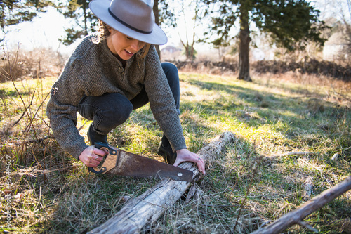 Woman Working with hand tools in farm field sawing fallen trees