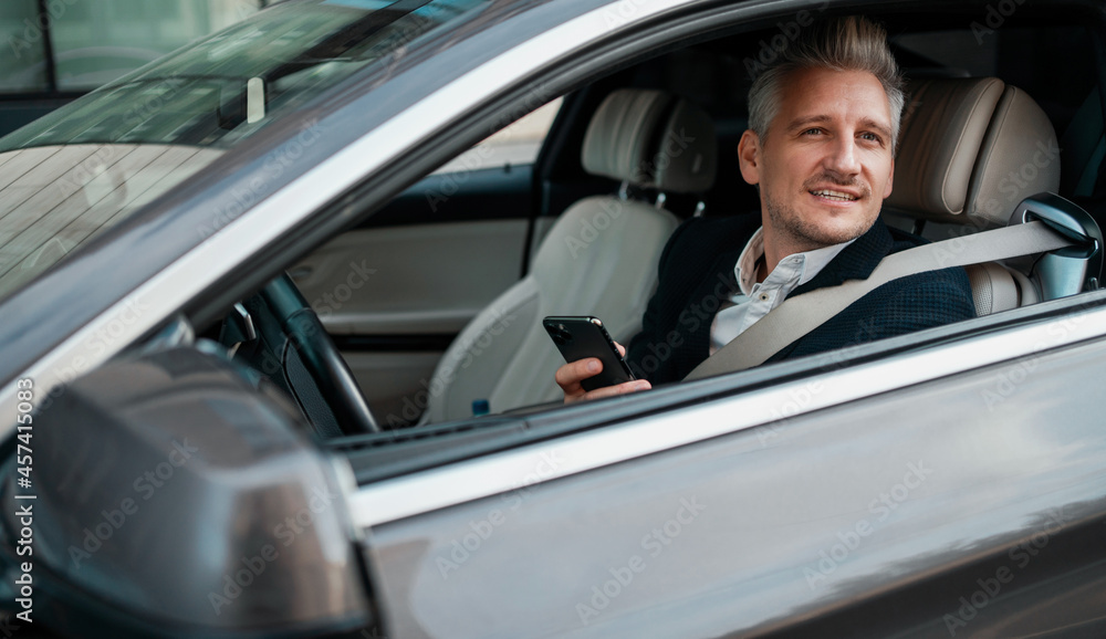A businessman man is sitting in a car. The consultant holds the phone and calls the client. The manager is happy to use the device. A businessman man is sitting in a car. The consultant holds the phone and calls the client. The manager is happy to use the device.