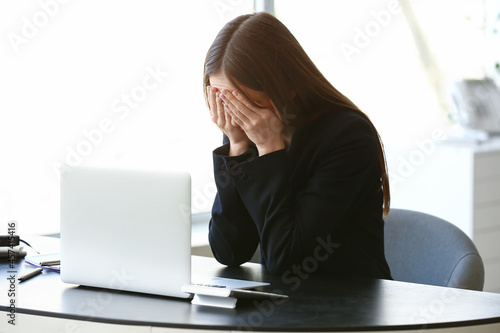 Crying young woman in offic...