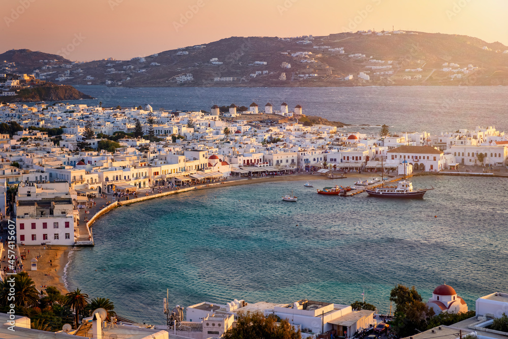 Elevated view of Mykonos island with the old harbour, the famous windmills above and old town during a soft summer sunset, Cyclades, Greece