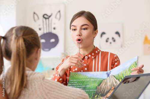 Speech therapist working with cute girl in clinic photo