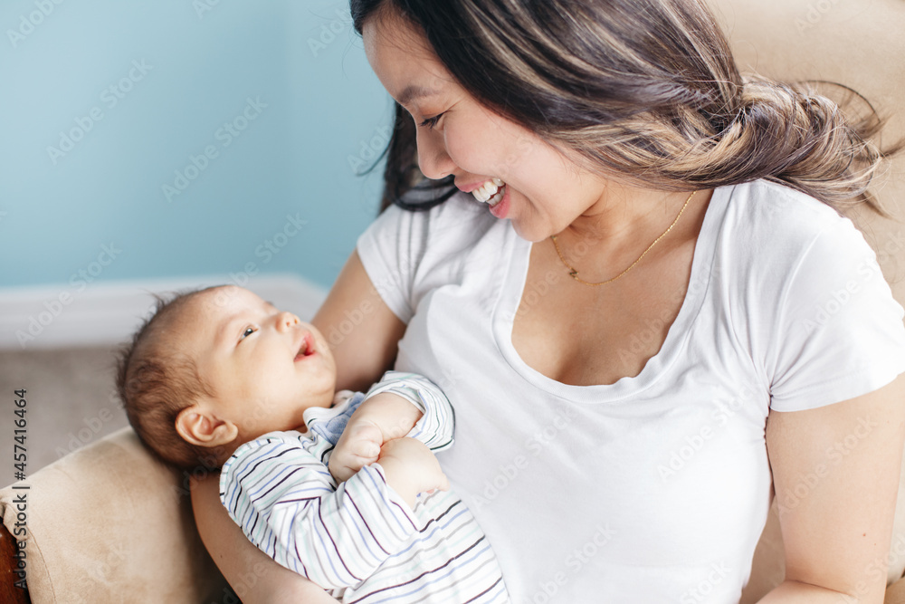 Asian mother holding rocking newborn infant baby son. Home lifestyle Asian mother holding rocking newborn infant baby son. Home lifestyle