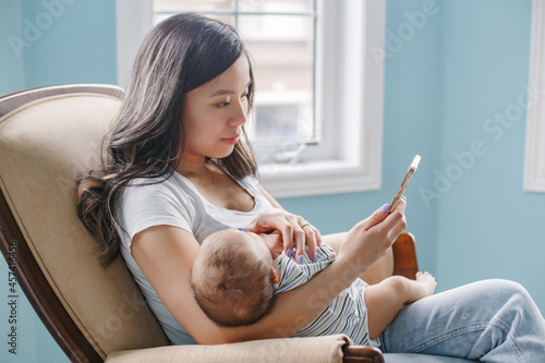 Asian mother holding newborn baby son and buy food online on Internet. photo