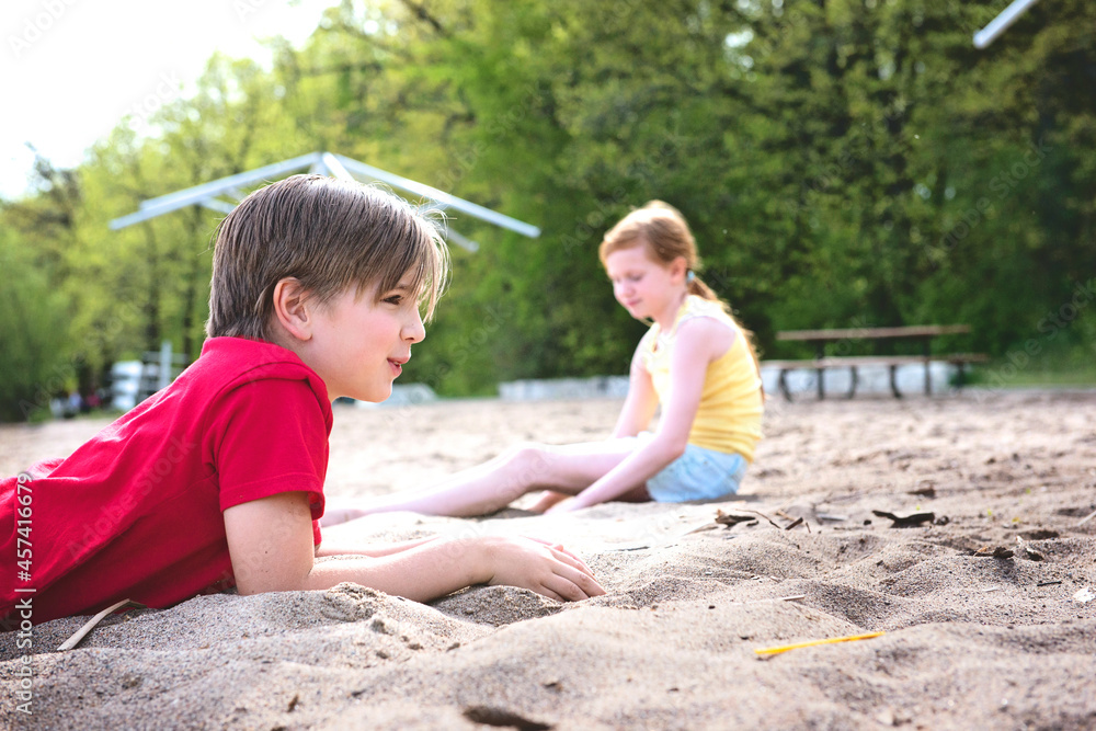 Young Boy and Girl Playing in the Sand by a Lake