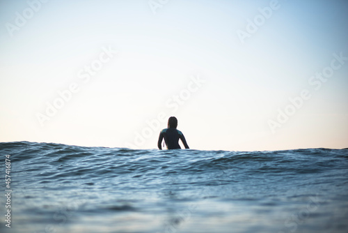 Individual Asian Woman in summer surf lineup at dawn photo