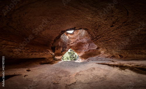 Image of a cave with a large entrance and a hole or window at the top photo