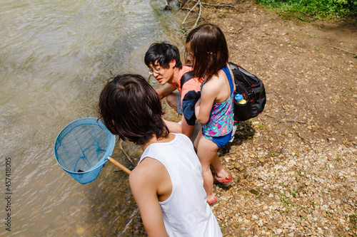 A father and two children stand by edge of creek with net exploring
