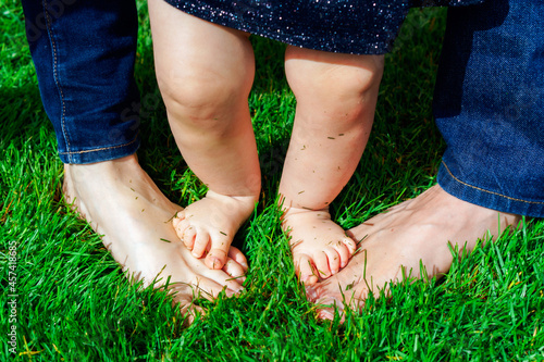 Close up of child`s feet standing on her parents feet in a grass. photo