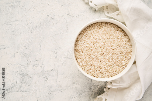 Top view of a bowl filled with raw white rice on a textured background photo