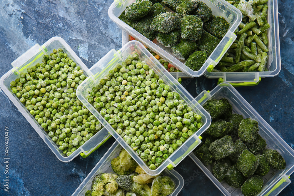Plastic containers with different frozen vegetables on color background Plastic containers with different frozen vegetables on color background