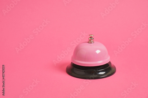 Ring alarm service pink metal bell on pink background.