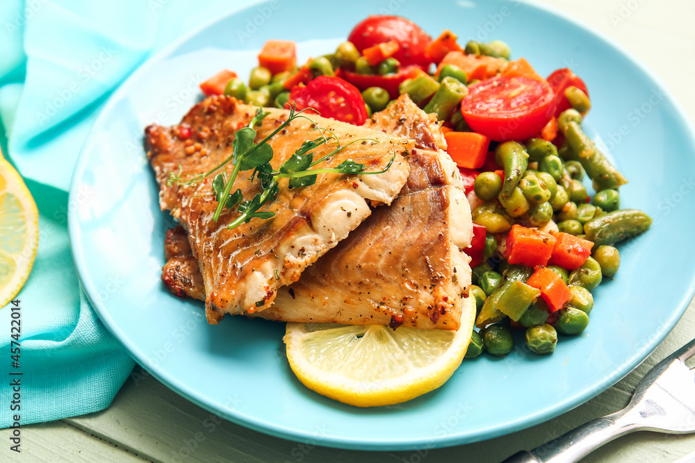 Plate with tasty baked cod fillet and vegetables on color wooden background, closeup Plate with tasty baked cod fillet and vegetables on color wooden background, closeup