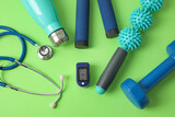 Pulse oximeter, stethoscope, bottle of water and sport equipment on color background, closeup