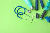 Pulse oximeter, stethoscope, bottle of water and sport equipment on color background