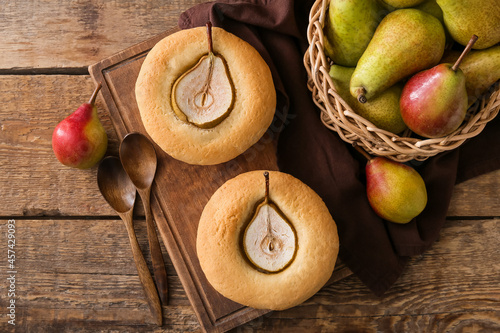 Board with tasty pear pot pies and fresh fruits on wooden background