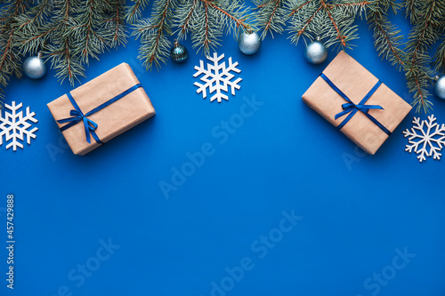 Fotografie, Obraz Christmas fir branches with presents and snowflakes on blue background