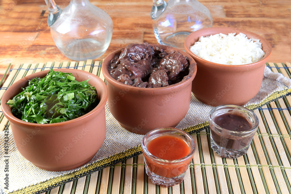 delicious Brazilian food feijoada with beans, pork, bacon, sausage with cabbage, rice, salad, spices and pepper. rustic cuisine. delicious Brazilian food feijoada with beans, pork, bacon, sausage with cabbage, rice, salad, spices and pepper. rustic cuisine.