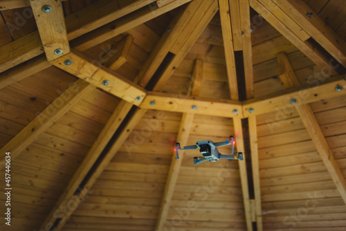 A flying unmanned aerial vehicle under a wooden roof. photo